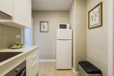 a kitchen with a white refrigerator and a stool at Novus Homes Barcelona Collblanc in Hospitalet de Llobregat