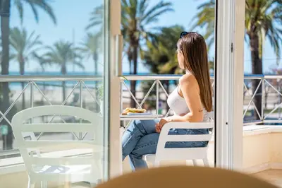 a pregnant woman sitting on a balcony looking out at the ocean at MAREA Hotel in Vilanova i la Geltrú