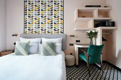 a bedroom with a bed and a desk and a green chair at Numa Barcelona Roca in Barcelona
