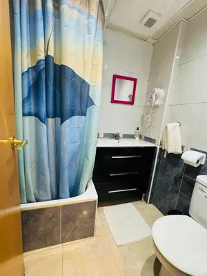a bathroom with a blue shower curtain and a toilet at Hostal Mont Thabor in Barcelona