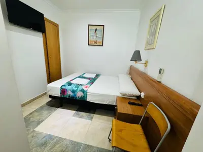 a small bedroom with a bed and a chair at Hostal Mont Thabor in Barcelona