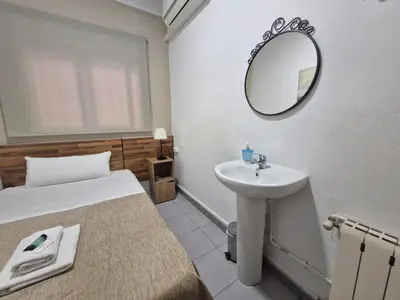 a bathroom with a bed and a sink and a mirror at Hostal Elkano in Barcelona