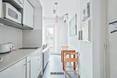a kitchen with white cabinets and a wooden chair at Alcam Pau Claris in Barcelona