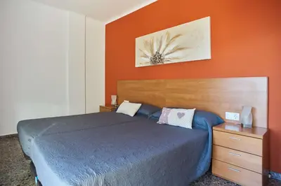 a bedroom with a blue bed and an orange wall at Manresa Apartamentos Turísticos in Manresa