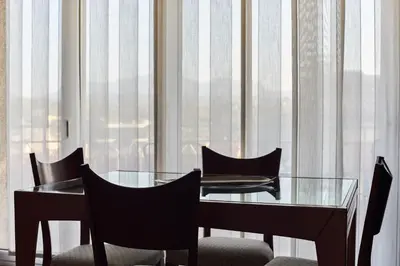 a glass table and chairs in a room with curtains at Manresa Apartamentos Turísticos in Manresa