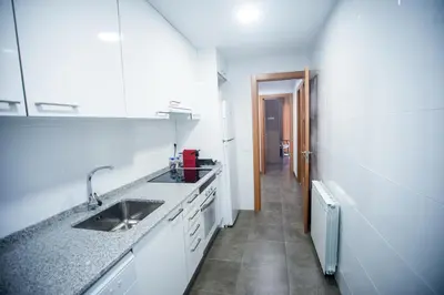 a white kitchen with a sink and a hallway at Manresa Apartamentos Turísticos in Manresa