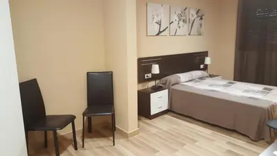 a bedroom with a bed and two chairs at Pensión Avenida in Vilafranca del Penedès