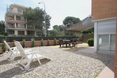 a pair of white lawn chairs sitting in a yard at Beach House Castelldefels in Castelldefels