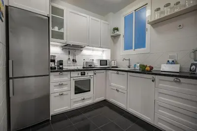 a kitchen with white cabinets and a refrigerator at Habitat Apartments Alaia in Barcelona