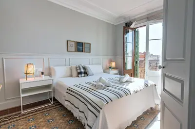 a white bedroom with a bed and a window at Habitat Apartments Grace in Barcelona