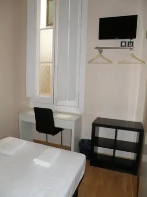a room with a bed and a chair and a television at Hotel Center Gran Via in Barcelona