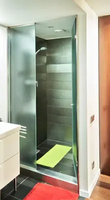a glass shower in a bathroom with a red rug at Apartamento Via Augusta 153 in Barcelona