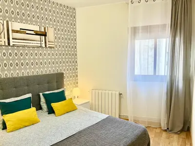 a bedroom with a bed with yellow and blue pillows at Comfortable renovated flat, WiFi! in Badalona