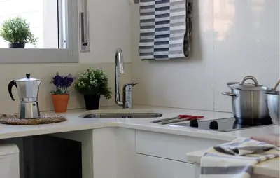 a kitchen counter with a sink and a stove at Sitges Ático 2 min a Playa San Sebastían in Sitges