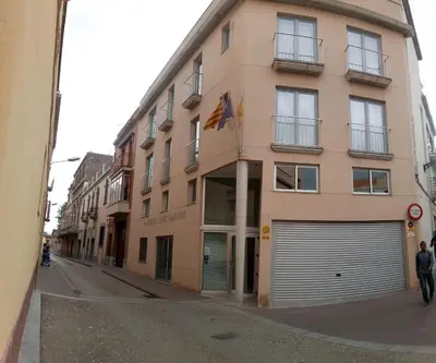 a large pink building with a garage on a street at Hostal Sant Sadurní in Sant Sadurní dʼAnoia
