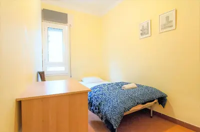 a bedroom with a bed and a desk and a window at Pintor Pahissa Rooms in Barcelona