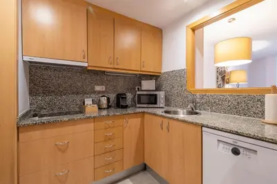 a kitchen with wooden cabinets and a sink and a microwave at Aspasios Plaza Real Apartments in Barcelona