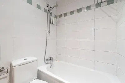 a white bathroom with a tub and a toilet at Aspasios Plaza Real Apartments in Barcelona