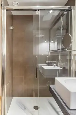 a bathroom with a glass shower and a sink at Hotel Vasanta in Barcelona
