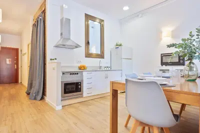 a white kitchen with a table and a dining room at Citytrip Barceloneta Beach in Barcelona