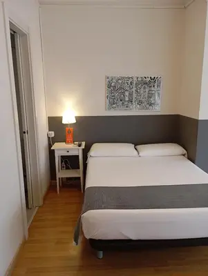 a bedroom with two beds and a table with a lamp at Hostal El Ninot in Barcelona
