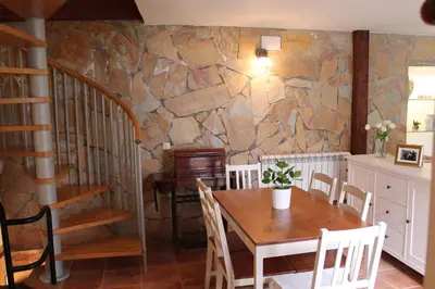 a dining room with a table and a stone wall at Old Navy House in Badalona