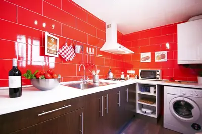 a red kitchen with a sink and a washing machine at Casa Tortilla Sagrada Familia in Barcelona
