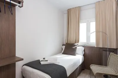 a bedroom with a bed and a window and a chair at Quartprimera Apartments in Barcelona