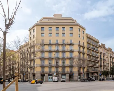 a large building with cars parked in front of it at The Corner Apartments by Aspasios in Barcelona