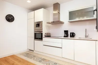 a kitchen with white cabinets and a clock on the wall at Akira Flats Urgell apartment in Barcelona