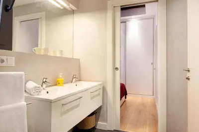 a white bathroom with a sink and a mirror at Akira Flats Urgell apartment in Barcelona