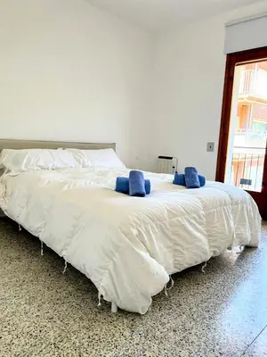 a large white bed with two blue pillows on it at Charming Attic with Pool and Seaviews in Arenys de Mar