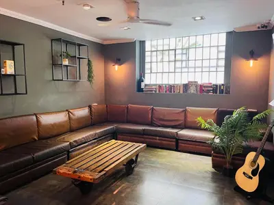 a living room with a brown couch and a guitar at Black Swan Hostel Barcelona in Barcelona