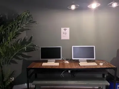 two computer monitors sitting on a wooden desk at Black Swan Hostel Barcelona in Barcelona