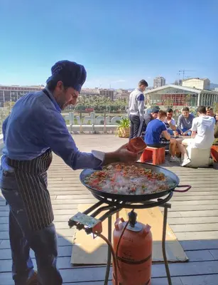 a man is preparing a pizza on a grill at Twentytu Hostel Barcelona in Barcelona
