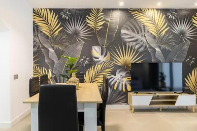 a dining room with a tv and a mural of palm leaves at Cosmo Apartments Consell de Cent - Plaza Universitat in Barcelona