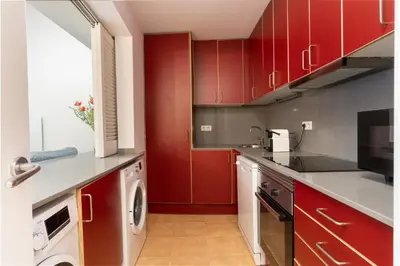 a kitchen with red cabinets and a washer and dryer at SibsBcn COLISEUM - Cozy and Central in Barcelona