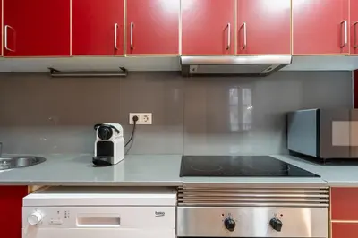 a kitchen with red cabinets and a stove at SibsBcn COLISEUM - Cozy and Central in Barcelona