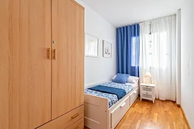 a small bedroom with a bed and a cabinet at Cálido apartamento con piscina en Barcelona in Ripollet