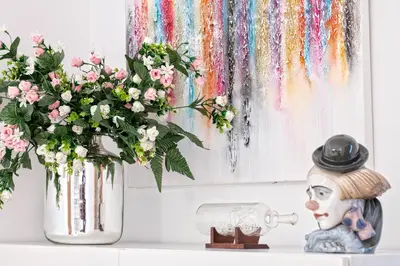 a table with a vase of flowers and a painting at Cálido apartamento con piscina en Barcelona in Ripollet