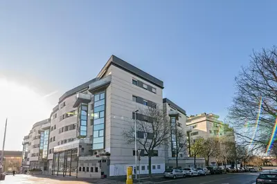 a tall white building on the side of a street at Cálido apartamento con piscina en Barcelona in Ripollet