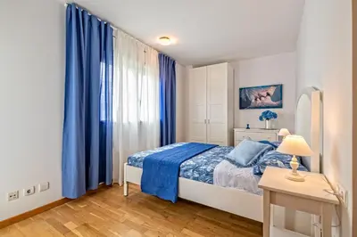 a bedroom with a bed and blue curtains at Apartamento lujo& piscina junto Barcelona Centro in Ripollet
