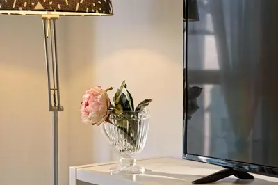 a vase with a pink flower on a table next to a lamp at Apartamento&piscina cerca de Barcelona in Ripollet