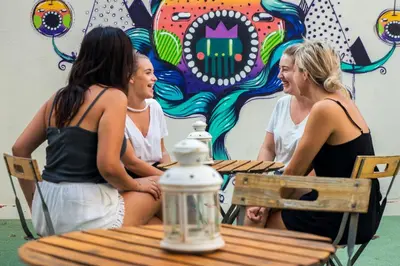 three women sitting at a table in front of a mural at Sant Jordi Hostels Gracia in Barcelona
