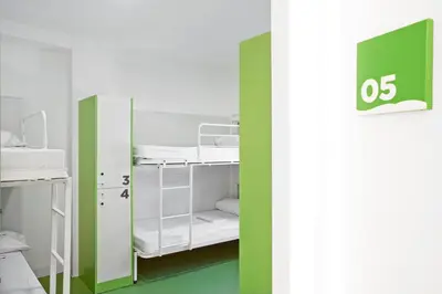 a room with white bunk beds and a green wall at Sant Jordi Hostels Gracia in Barcelona