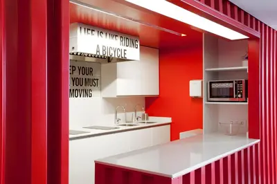 a kitchen with red walls and a white counter top at Sant Jordi Hostels Gracia in Barcelona