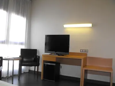 a room with a desk with a television and two chairs at Hotel Pere III El Gran in Vilafranca del Penedès