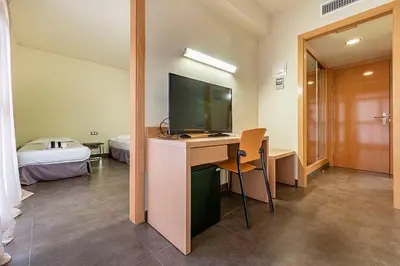 a room with a desk with a television and a bed at Hotel Pere III El Gran in Vilafranca del Penedès