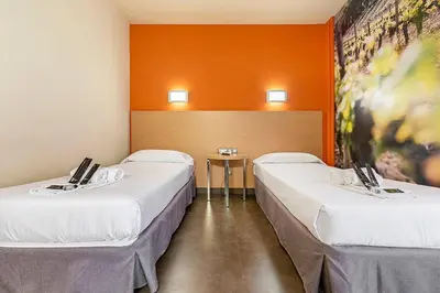 three beds in a room with orange walls at Hotel Pere III El Gran in Vilafranca del Penedès