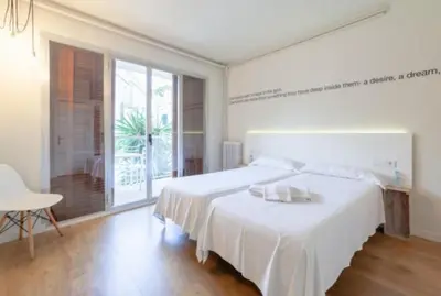 a white bedroom with a large bed and a table at Dynamic Hotels Caldetes Barcelona in Caldes d'Estrac